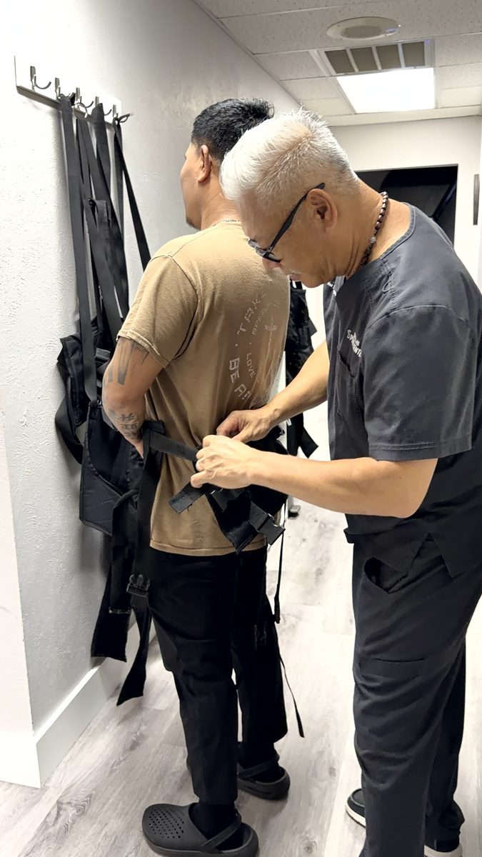 Dr. Hoa Nguyen fitting a spinal decompression harness on a patient in Carrollton, TX
