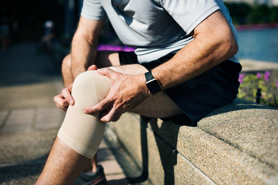 Man holding his leg in pain from a sports injury while jogging