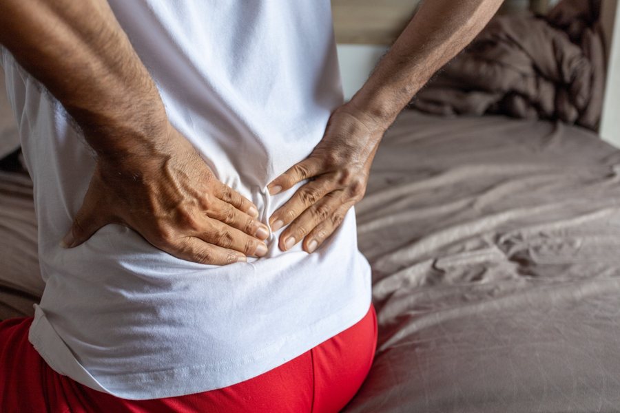 Man lying in bed with sciatica pain radiating from his lower back down his leg
