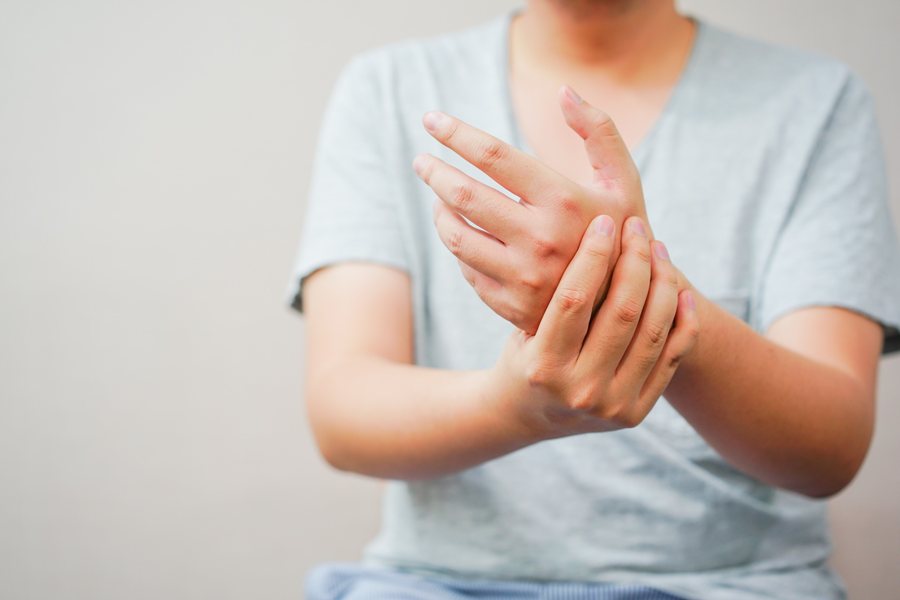 Woman holding her hand because of numbness and tingling
